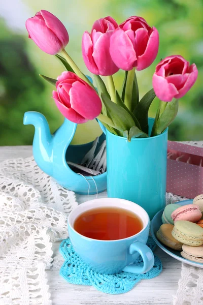 Composizione di fiori primaverili, tè e biscotti sul tavolo su sfondo naturale — Foto Stock