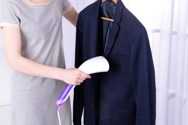 Women steaming shirt in room — Stock Photo, Image