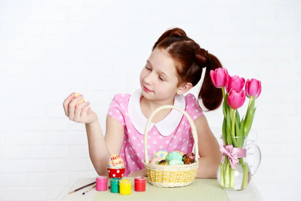 Cute girl decorates Easter eggs, on light background — Stock Photo, Image