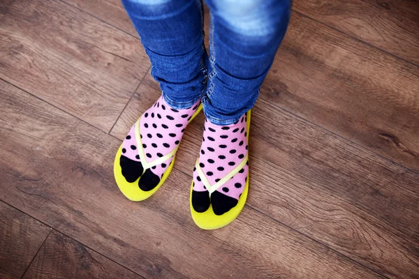 Female feet in socks with pink flip-flops, on floor background — Stock Photo, Image