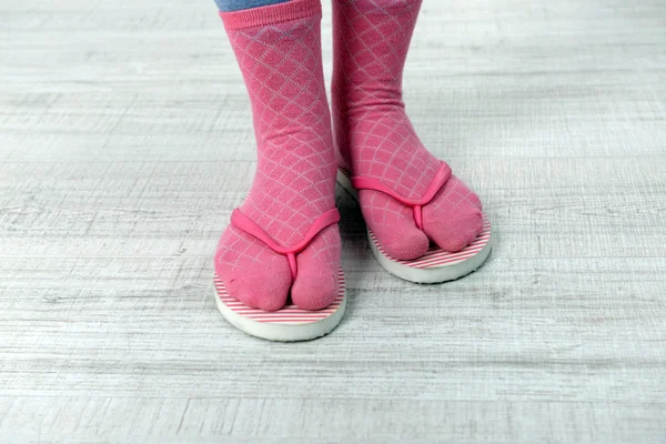 Pés femininos em meias com chinelos rosa, no fundo do chão — Fotografia de Stock