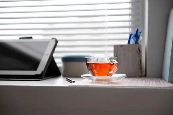 PC tablet, notebook and cup of tea on windowsill. Working place concept — Stock Photo, Image