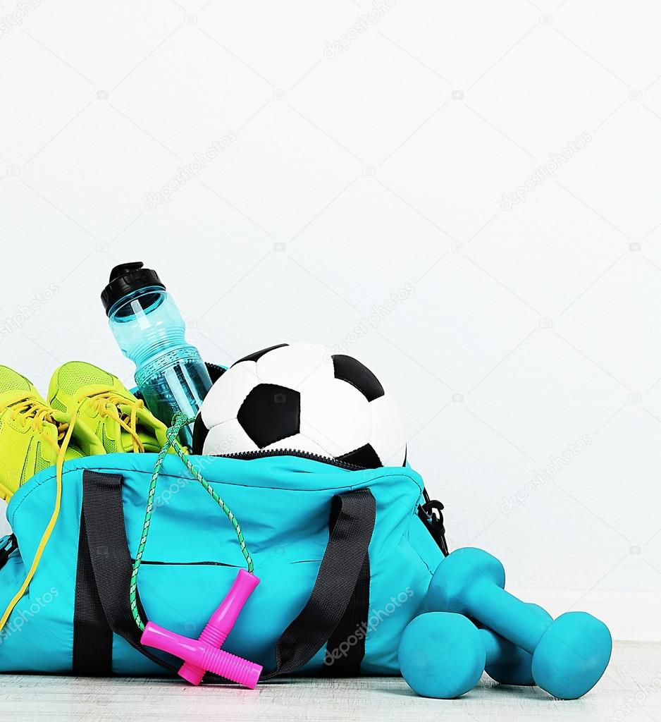 Sports bag with sports equipment in room