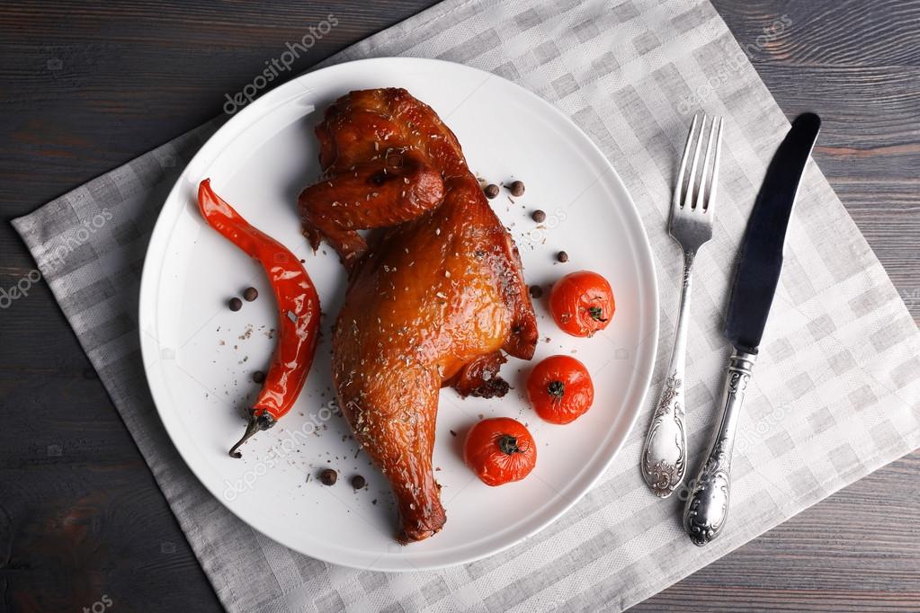 Smoked chicken leg  with vegetables on plate on table close up