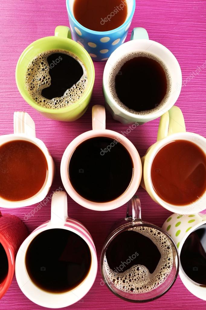 Many cups of coffee on pink table, top view