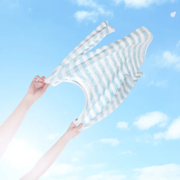 Ręce trzymając latające koszula na tle nieba — Zdjęcie stockowe