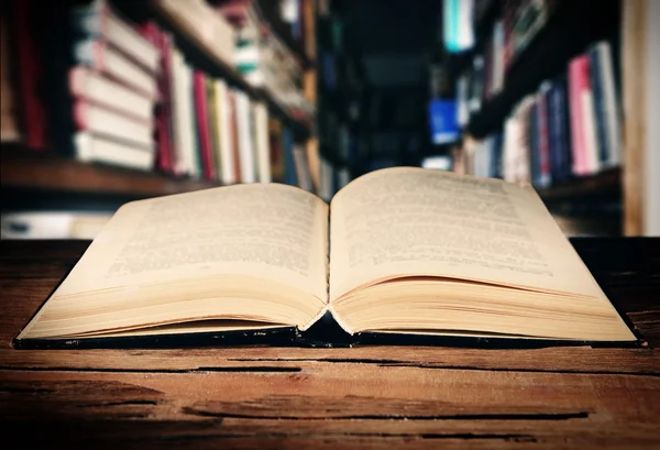 Libro abierto sobre la mesa en los estantes de fondo — Foto de Stock