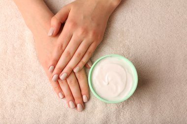 Kumaş arka plan üzerinde krema kavanozu ile eller