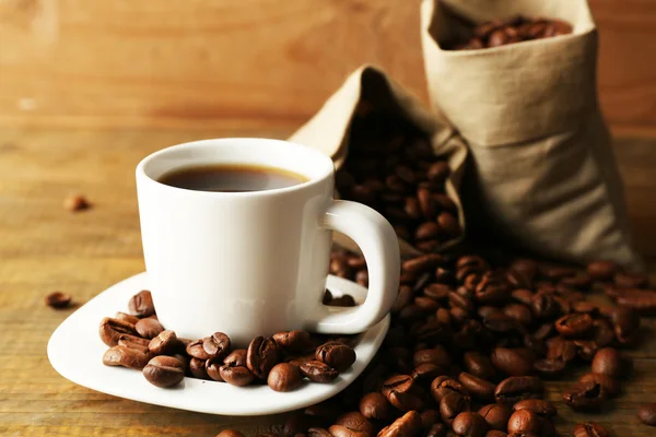 Secangkir kopi dengan kacang pada latar belakang kayu pedesaan — Stok Foto
