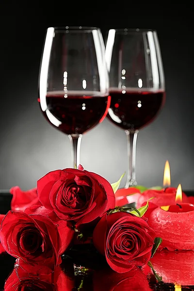 Композиція з червоним вином в окулярах, червоною трояндою та декоративним серцем на темному тлі — стокове фото