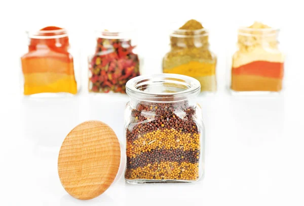 Verschillende soorten specerijen in glazen flessen geïsoleerd op wit — Stockfoto