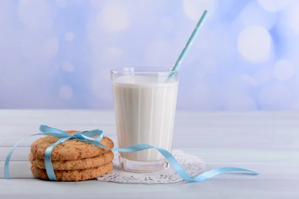 Tasty cookies and glass of milk on color wooden table, on bright background — Stock Photo, Image