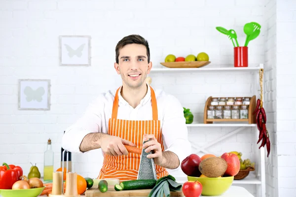 Homem à mesa com diferentes produtos e utensílio na cozinha no fundo da parede branca — Fotografia de Stock
