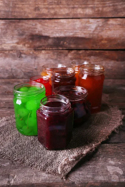 Homemade jars of fruits jam on rustic wooden background — Stock Photo, Image