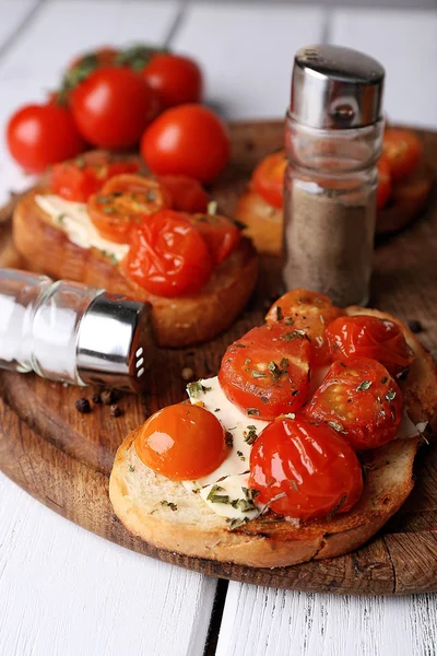 Segmenten van wit geroosterd brood met boter en Ingeblikte tomaten op houten planken achtergrondkleur — Stockfoto