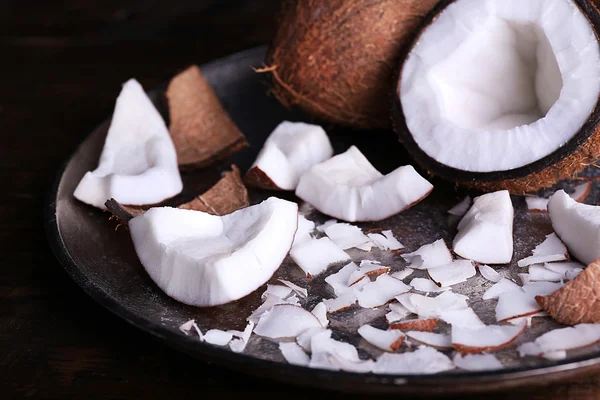 Gebarsten kokosnoot op metalen plaat op rustieke houten tafel achtergrond — Stockfoto