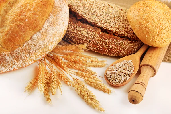 Fresh bread with wheat and wooden spoon of sunflower seeds isolated on white — Stock Photo, Image