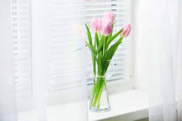 Piękne różowe tulipany w szklanym wazonie na parapecie tło — Zdjęcie stockowe