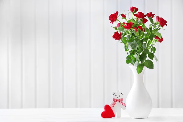 Bouquet di rose rosse in vaso su fondo di assi di legno — Foto Stock