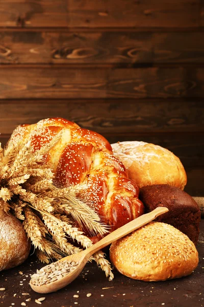 Diferente pan con espigas y semillas de girasol sobre fondo de madera —  Fotos de Stock
