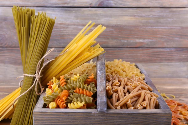Different types of pasta in box on wooden background — Stock Photo, Image
