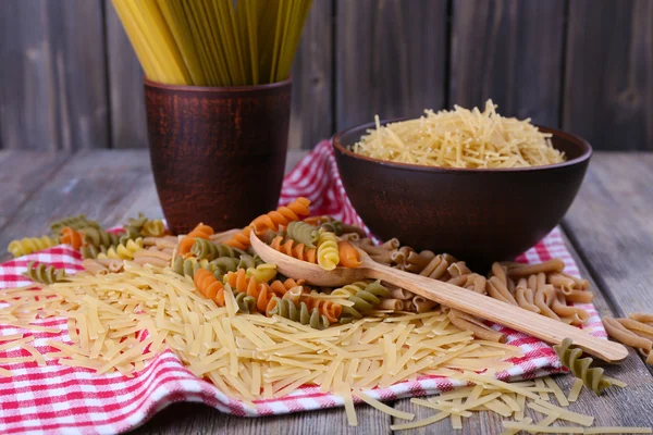 Diferentes tipos de pasta en servilleta sobre fondo de madera —  Fotos de Stock