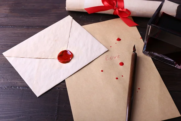 Envelope with pen and ink on wooden background — Stock Photo, Image