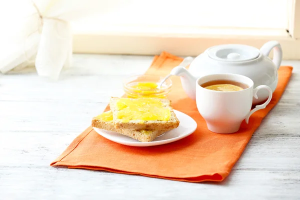 Toasts mit Honig auf Teller und Tasse Tee auf hellem Hintergrund — Stockfoto