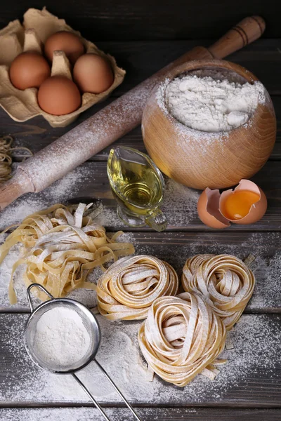 Raw homemade pasta and ingredients for pasta on wooden background — Stock Photo, Image