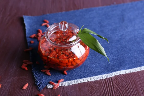 Jar of goji berry jam on napkin on wooden background — Stock Photo, Image