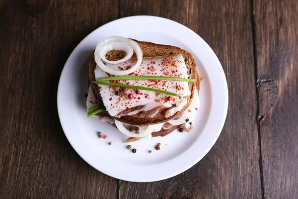 Сэндвичи с салом и луком на деревянном фоне — стоковое фото