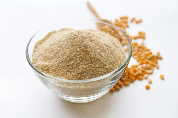 Glass bowl with flour and corn grains isolated on white — Stock Photo, Image