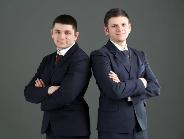 Two handsome businessmen on gray background — Stock Photo, Image