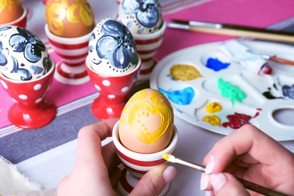 Mujer joven pintando huevos de Pascua en la mesa de cerca —  Fotos de Stock
