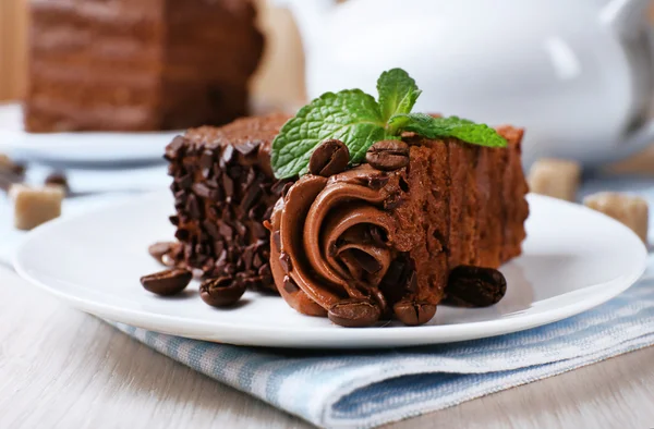 Des morceaux savoureux de gâteau au chocolat à la menthe et à la cannelle sur une table en bois et des planches floues — Photo