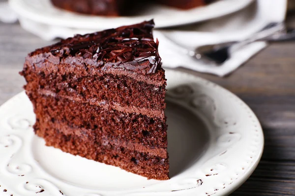 Delicioso pastel de chocolate en plato blanco sobre fondo de mesa de madera, primer plano — Foto de Stock