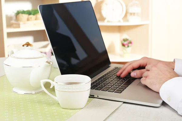 Man working on laptop on wooden table on home interior background — Stock Photo, Image