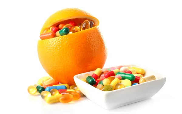 Pomarańczowe owoce i kolorowe tabletki, na białym tle — Zdjęcie stockowe