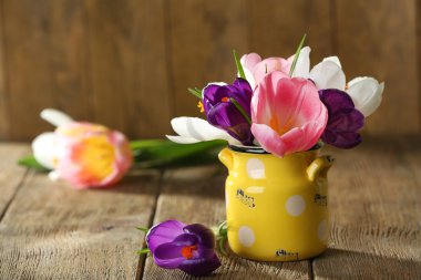 Ahşap zemin üzerine sarı tencerede güzel bahar çiçekleri