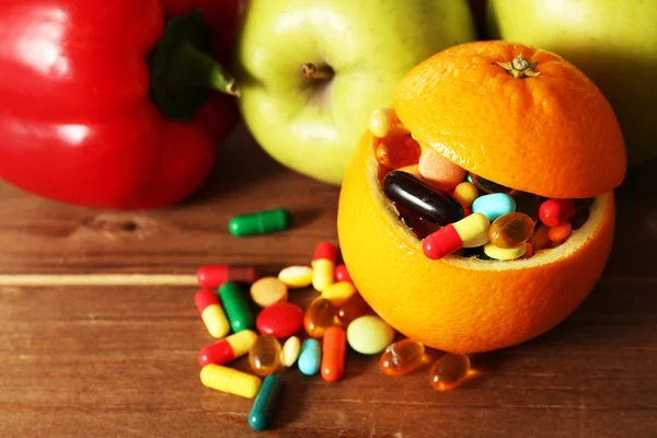 橙色水果满五颜六色的药丸，木制背景 — 图库照片