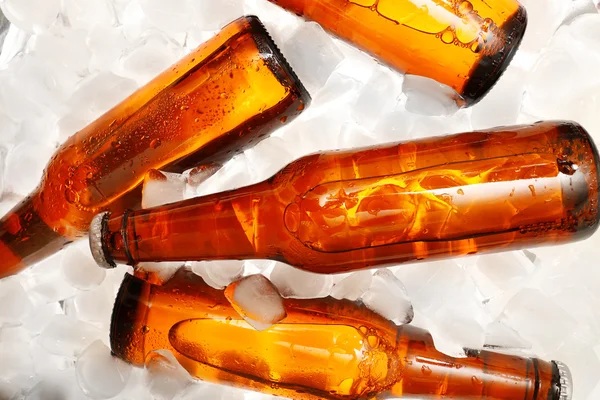 Glass bottles of beer with ice cubes, closeup — Stock Photo, Image