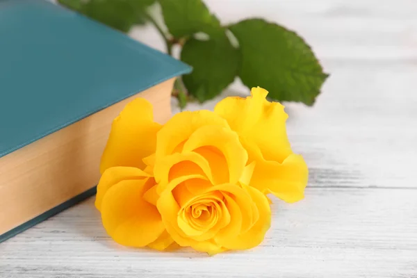 Rosa amarela com livro sobre mesa de madeira, close-up — Fotografia de Stock