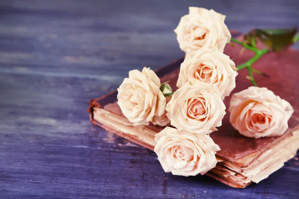 Όμορφα τριαντάφυλλα με vintage βιβλίο σε ξύλινο τραπέζι φόντο χρώμα — Φωτογραφία Αρχείου