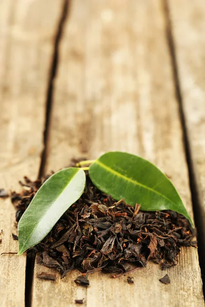 Té negro con hoja sobre mesa de madera vieja —  Fotos de Stock