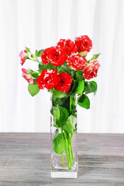 Beautiful roses in vase on table on light background — Stock Photo, Image
