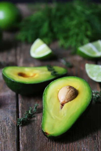 Sliced avocado with lime and herb on wooden table, closeup — Stock Photo, Image