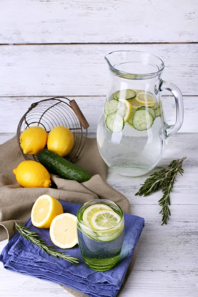 Fresh water with lemon and cucumber in glassware on wooden background — Stock Photo, Image