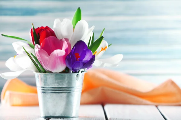 Prachtige Lentebloemen in metalen emmer op kleur achtergrond — Stockfoto