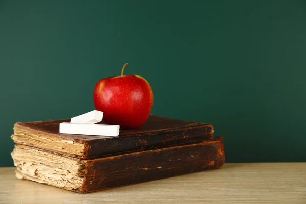 Libros antiguos, manzana y tiza sobre fondo de pizarra — Foto de Stock