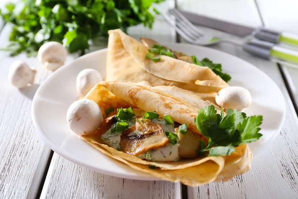 Pancakes with creamy mushrooms and greens in plate on wooden table, closeup — Stock Photo, Image